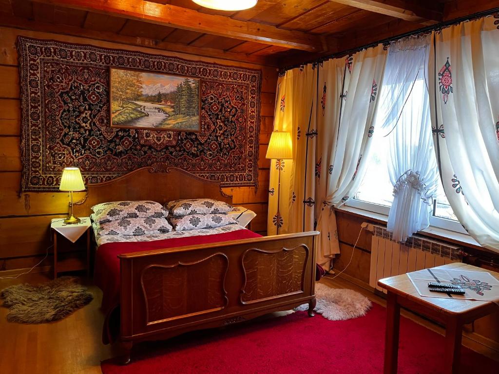 a bedroom with a bed and a table and a window at Domek Pod Kogutkiem Na Dolinie in Bukowina Tatrzańska