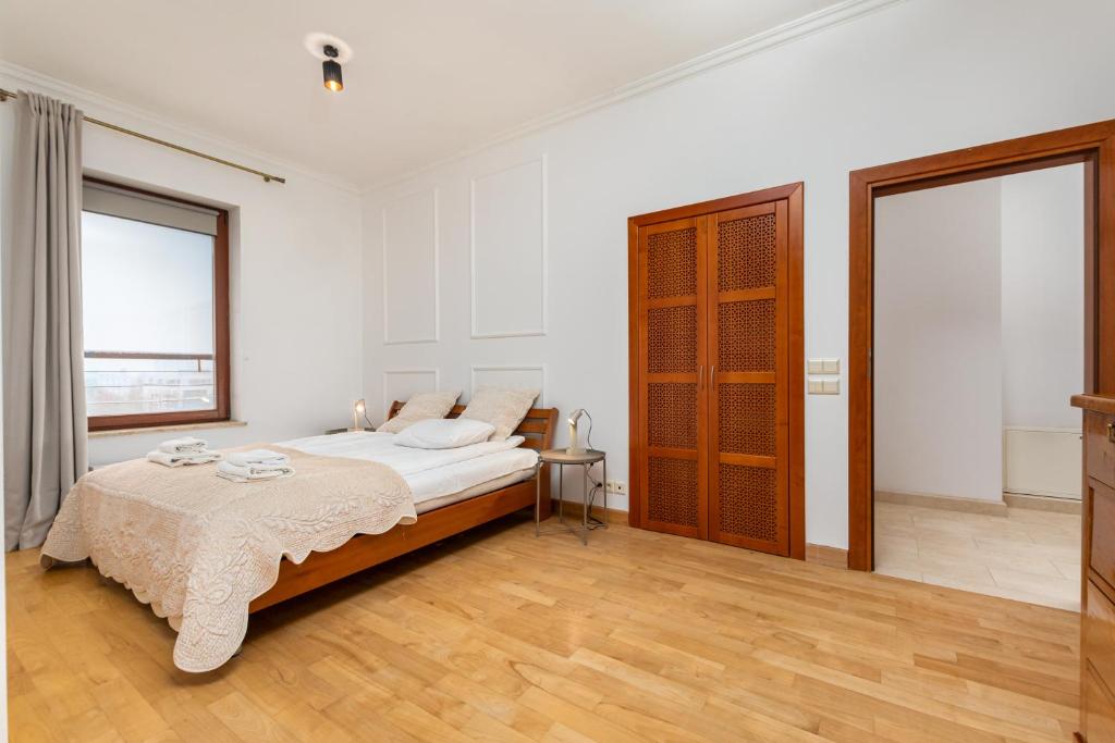 ein weißes Schlafzimmer mit einem Bett und zwei Fenstern in der Unterkunft Tagore 3 by Homeprime in Warschau