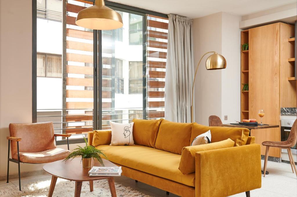ein Wohnzimmer mit einem gelben Sofa und Stühlen in der Unterkunft Stayhere Casablanca - Gauthier 3 - Urban Residence in Casablanca