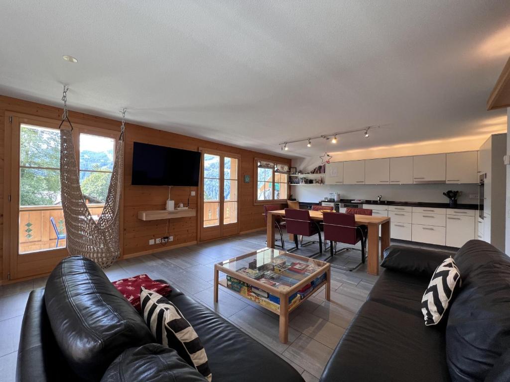 ein Wohnzimmer mit einem schwarzen Ledersofa und einem Tisch in der Unterkunft Chalet Bergrose 3 in Wengen