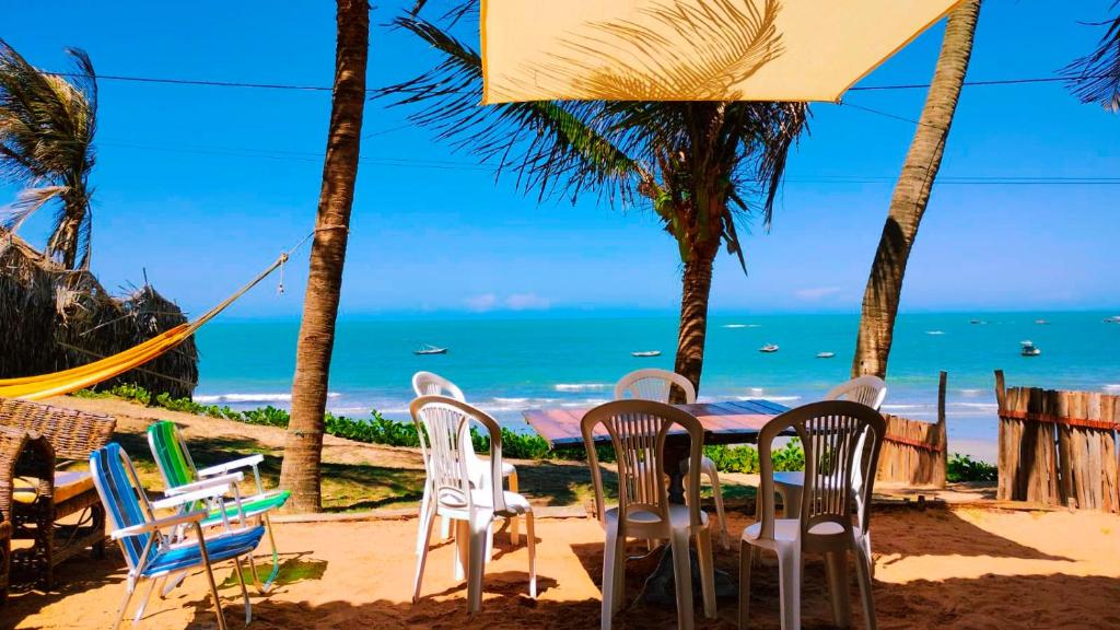 een tafel en stoelen op een strand met uitzicht op de oceaan bij Casa da Peroba Sol in Icapuí