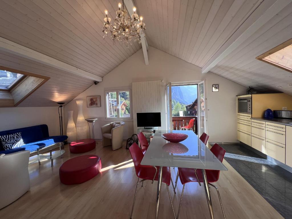 uma sala de estar com uma mesa branca e cadeiras vermelhas em Chalet Tilia Penthouse em Wengen