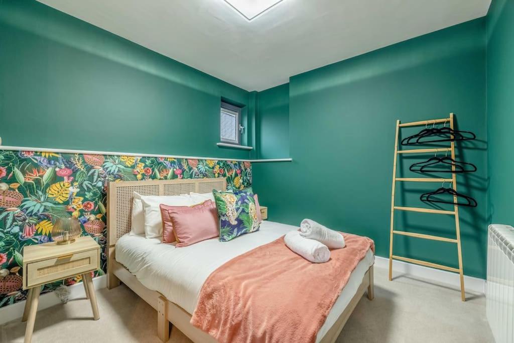 a bedroom with blue walls and a bed with pink pillows at Charming 1BR Apartment Near Windsor Castle in Windsor