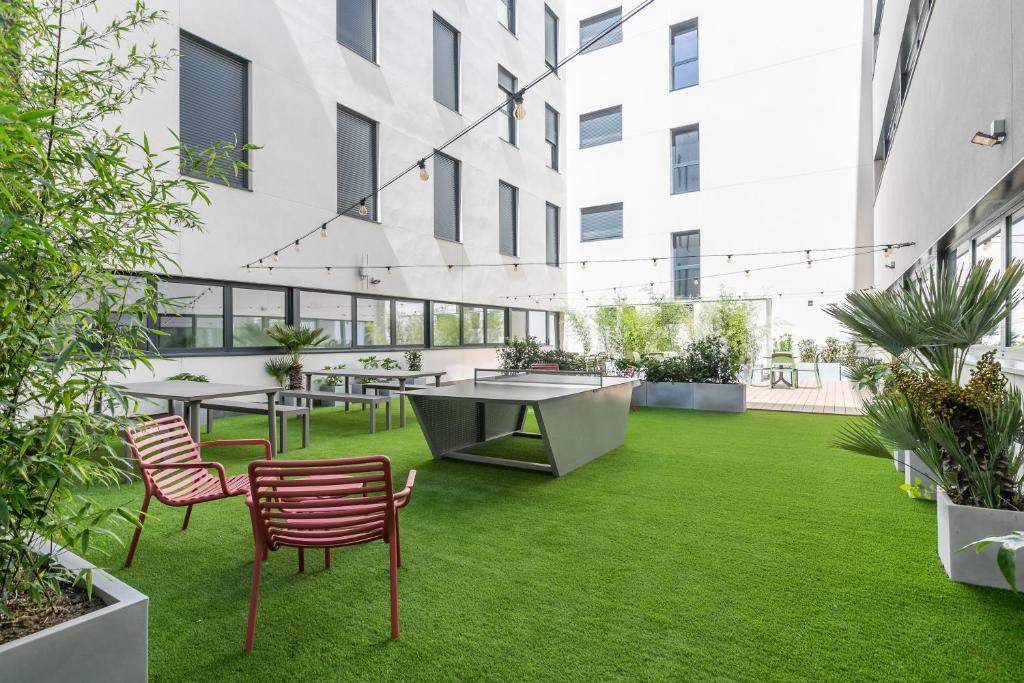 an internal courtyard with tables and chairs and grass at Micampus Getafe II Student Residence in Getafe