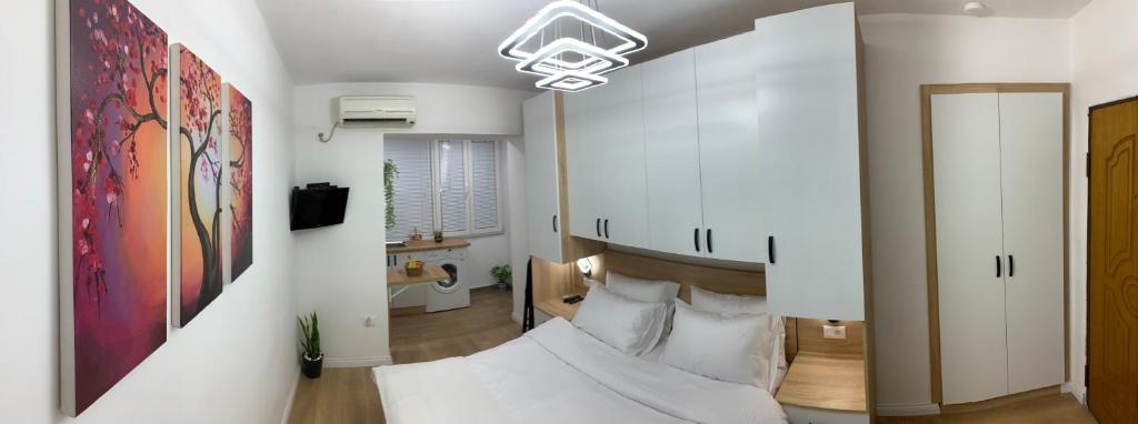 Habitación con paredes blancas y cama con almohadas. en Tirana Apartment, en Tirana