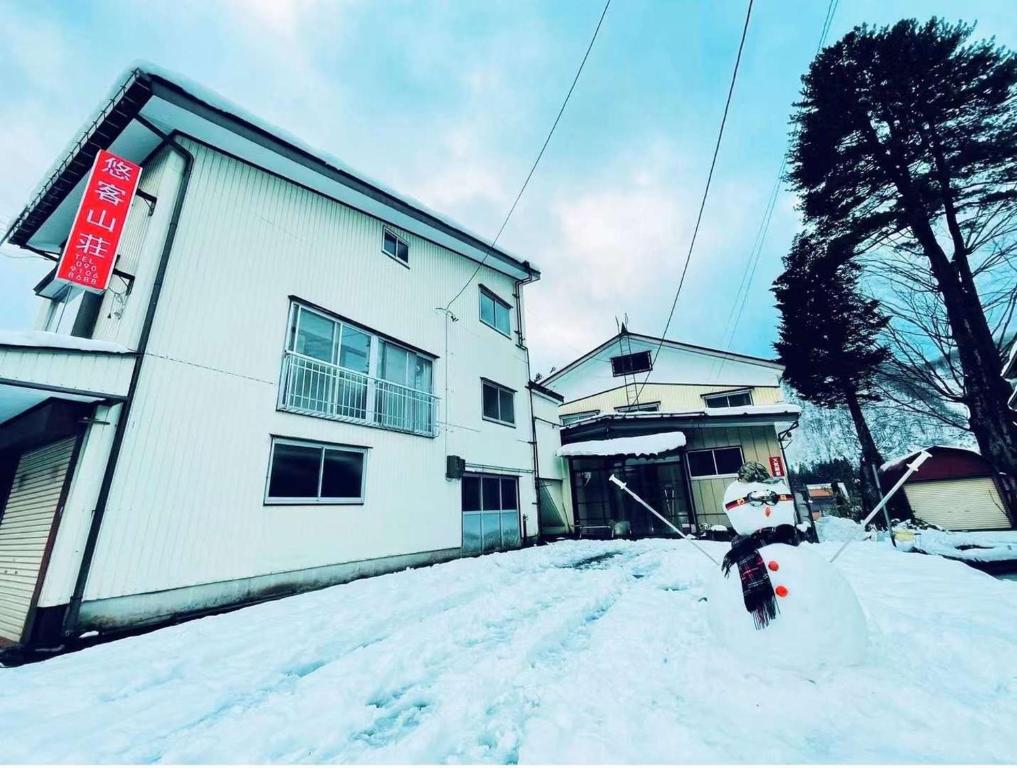 uma pessoa de pé na neve em frente a um edifício em 悠客山荘 em Yuzawa