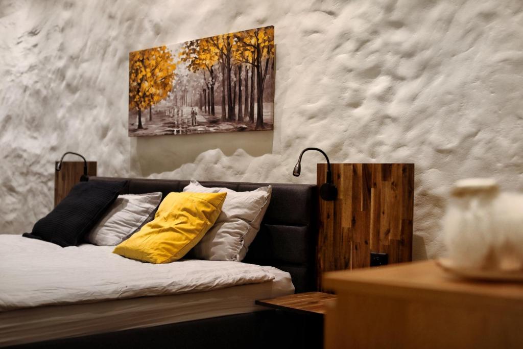 a bedroom with a bed with yellow pillows and a painting at Town Hall Square Apartment in Tallinn
