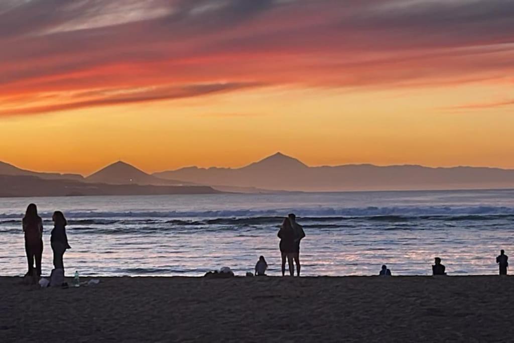 eine Gruppe von Menschen, die bei Sonnenuntergang am Strand stehen in der Unterkunft Oasis in Las Palmas de Gran Canaria