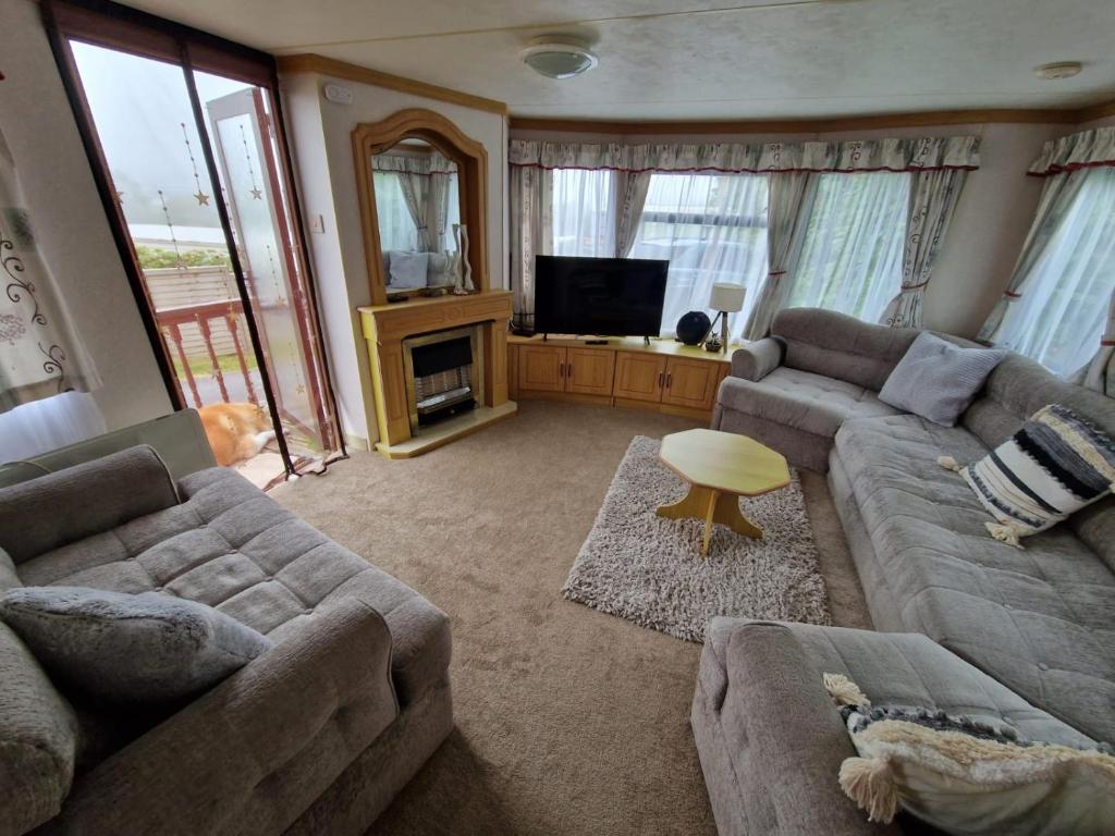a living room with two couches and a television at Caravan F8 Aberystwyth Holiday Village in Aberystwyth