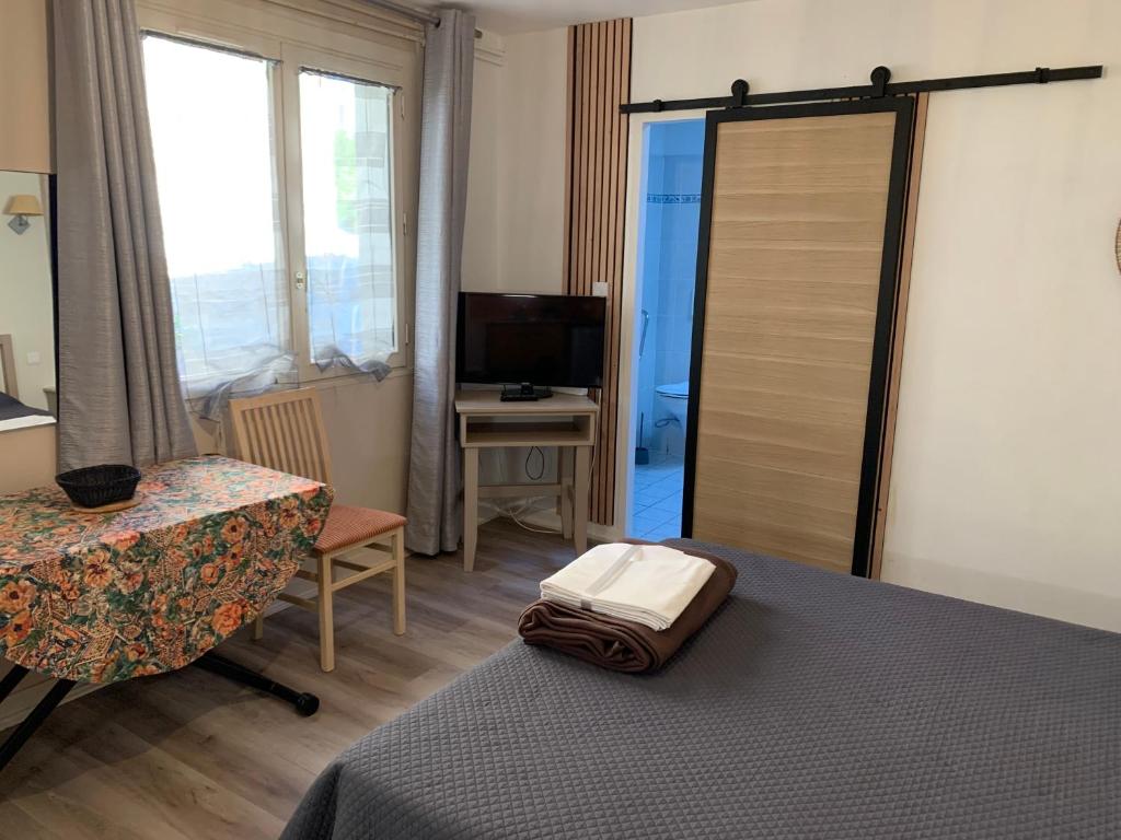 a bedroom with a bed and a desk and a television at Résidence Le Rochebonne in Saint Malo