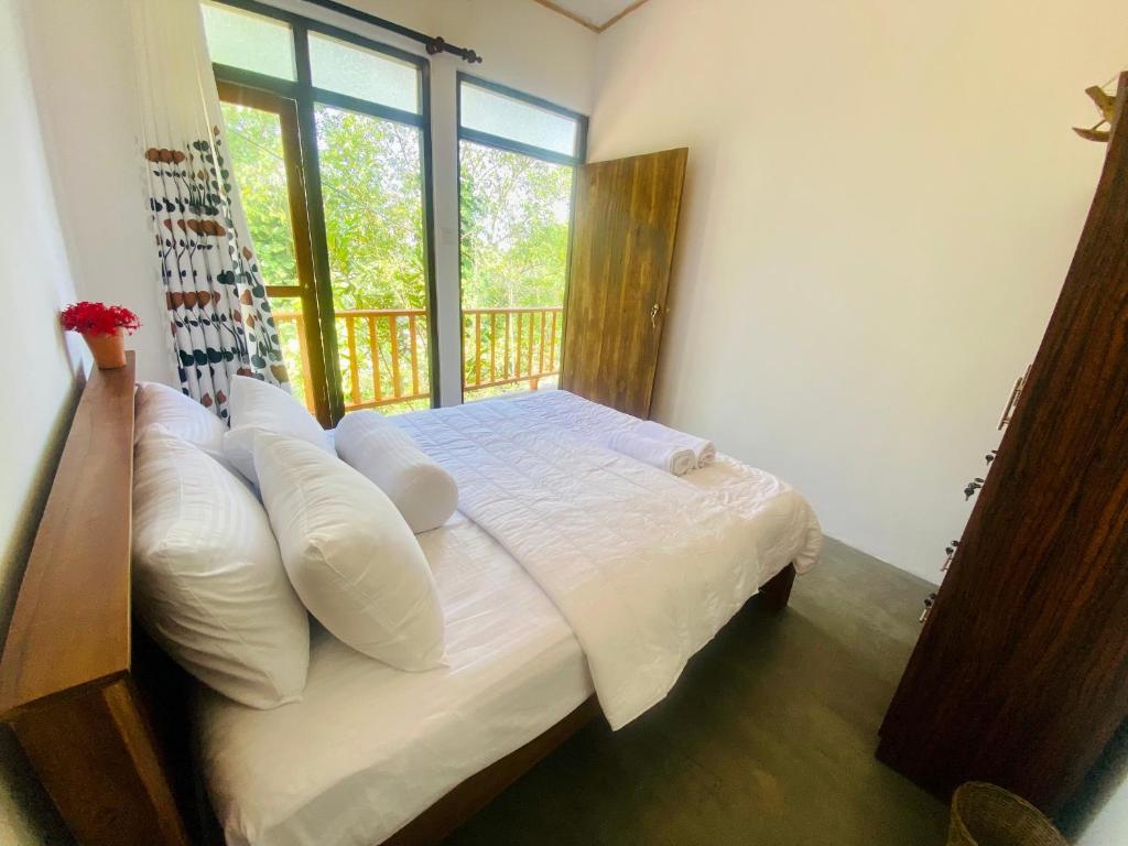 um quarto com uma cama com almofadas brancas e uma janela em Jungle Beach Inn em Unawatuna