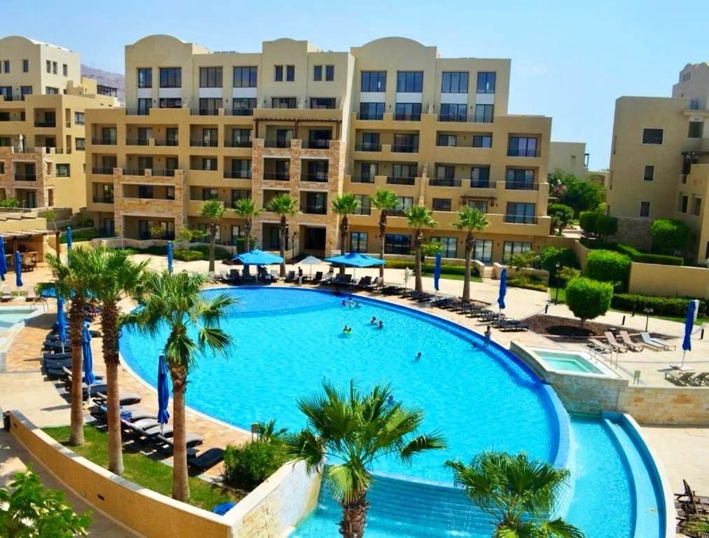 a large swimming pool with palm trees and buildings at EP4 Samarah Resort in Sowayma