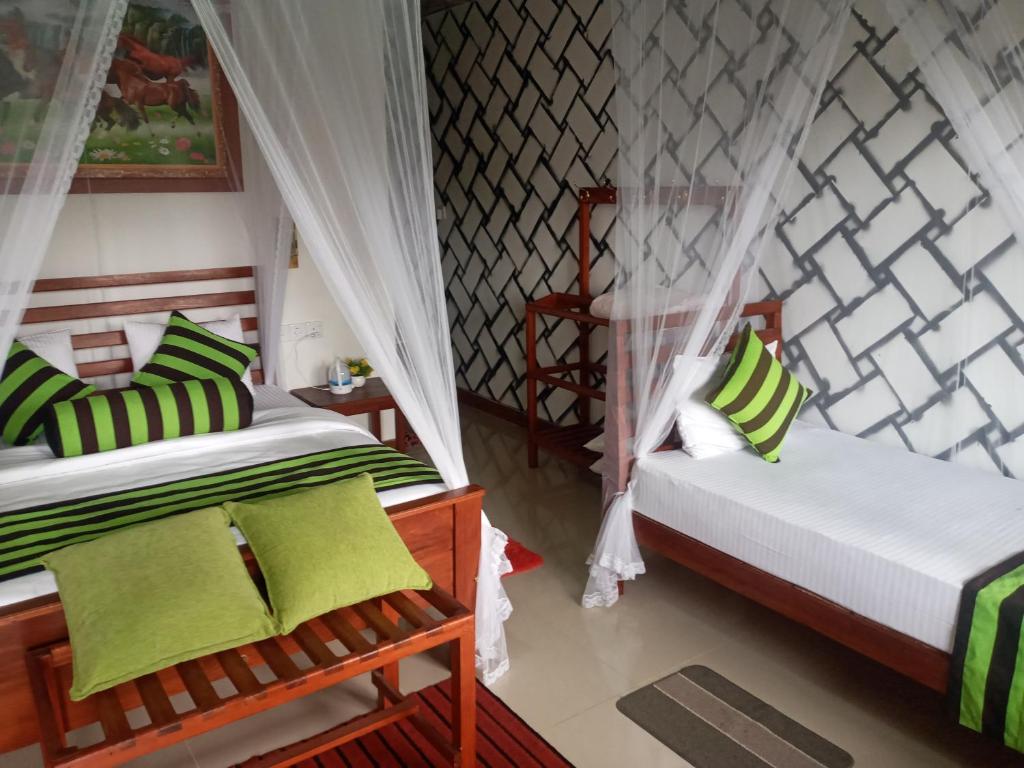 two beds in a room with green and white pillows at NETHSARA cottage in Ella