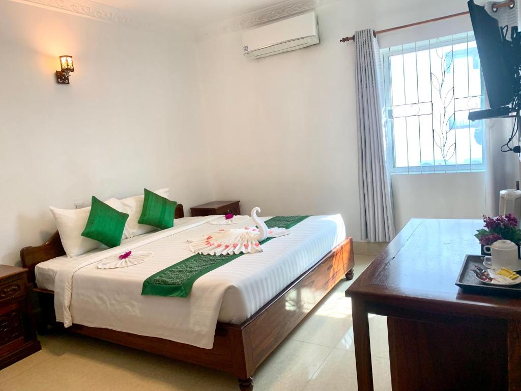 a bedroom with a bed with green and white pillows at The One by Nika in Siem Reap