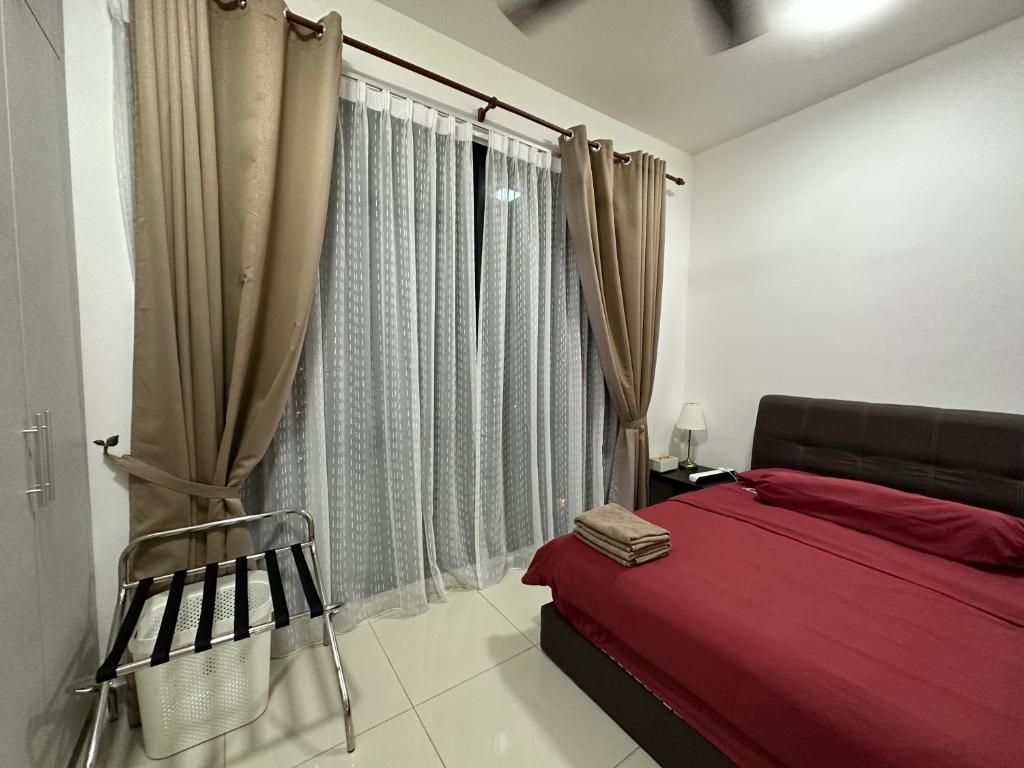 a bedroom with a red bed and a chair next to a window at Kyra Homestay Centrus SOHO Cyberjaya *wifi and pool* in Cyberjaya