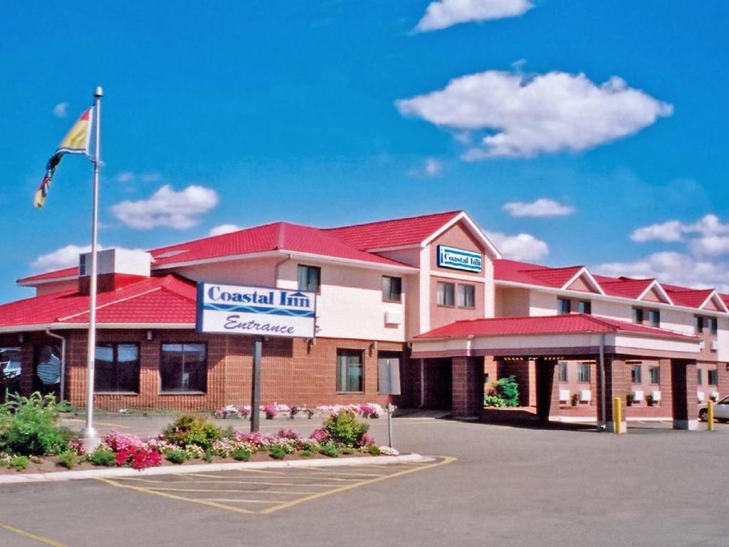 a hotel with a flag in a parking lot at Coastal Inn Moncton/ Dieppe in Moncton