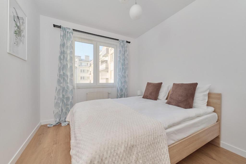 a white bedroom with a bed and a window at Cozy Apartment Klimasa with Balcony in Wrocław by Renters in Wrocław