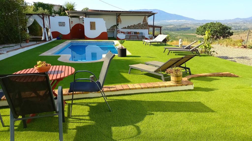 un patio con piscina y sillas y una casa en Casa de la Vida Málaga en Pizarra