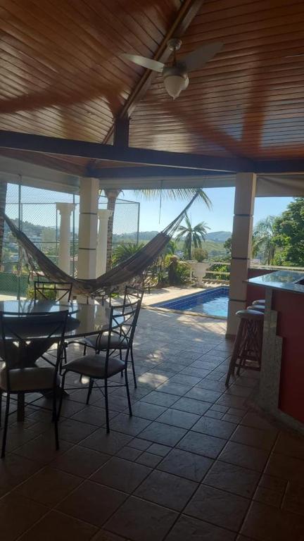 a hammock in a porch with a table and chairs at Escarpas do Lago in Capitólio