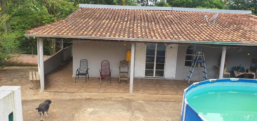 uma casa com uma piscina e um cão de pé na frente dela em Chácara Cuesta Machado em Botucatu