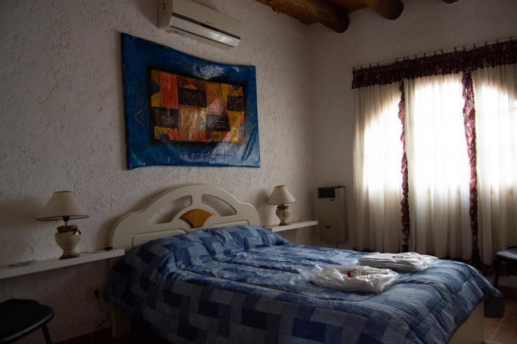 a bedroom with a bed with a blue and white comforter at Rincón Spa Seule in Ciudad Lujan de Cuyo