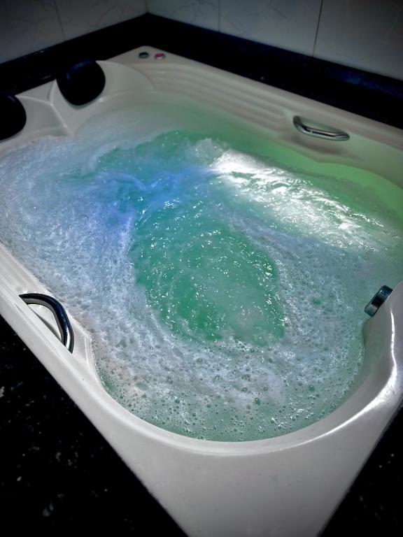 a bath tub filled with blue and green water at Casa de Praia in Imbituba