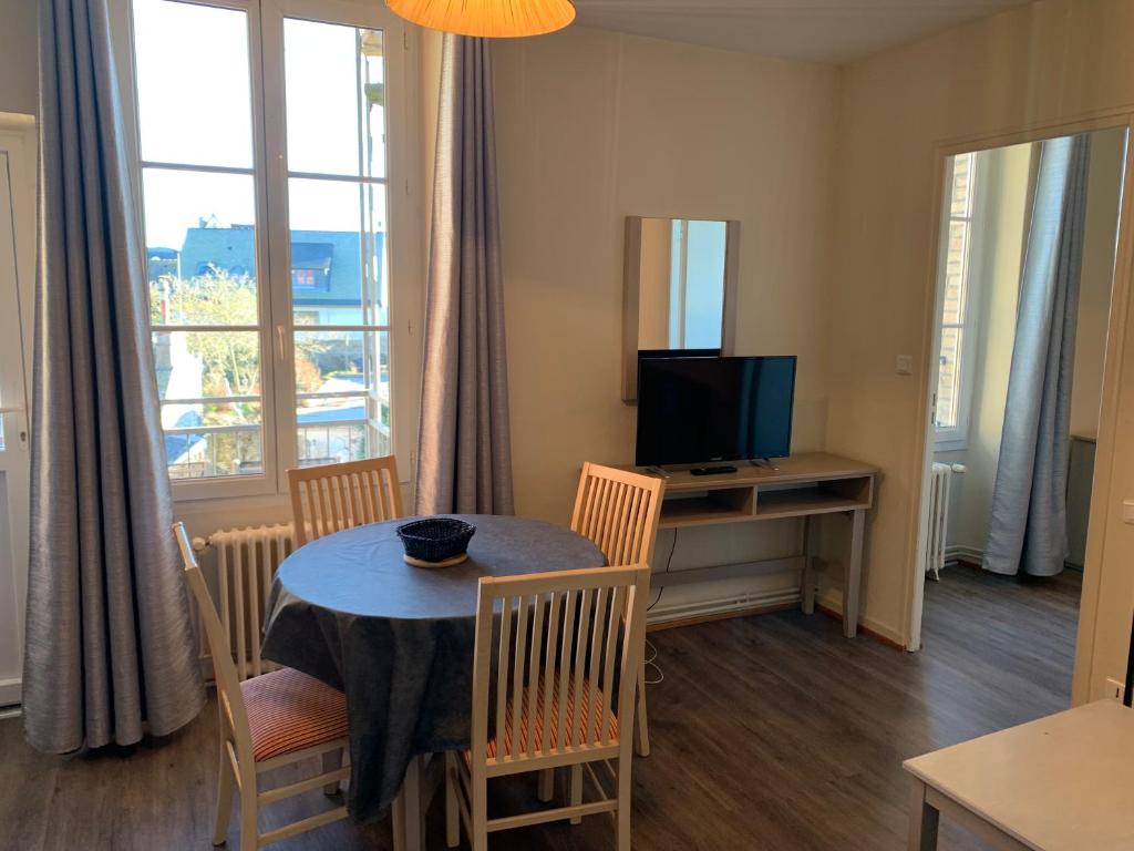 a dining room with a table and chairs and a television at Résidence Le Rochebonne in Saint Malo