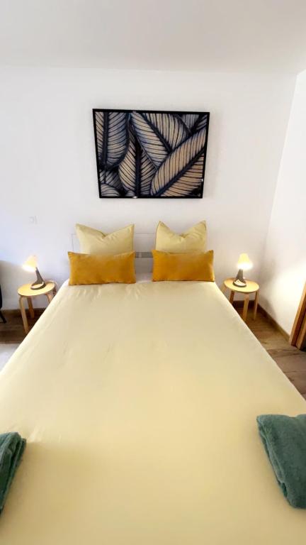 - une chambre avec un grand lit blanc et des oreillers jaunes dans l'établissement Chambre provençale, à Arles