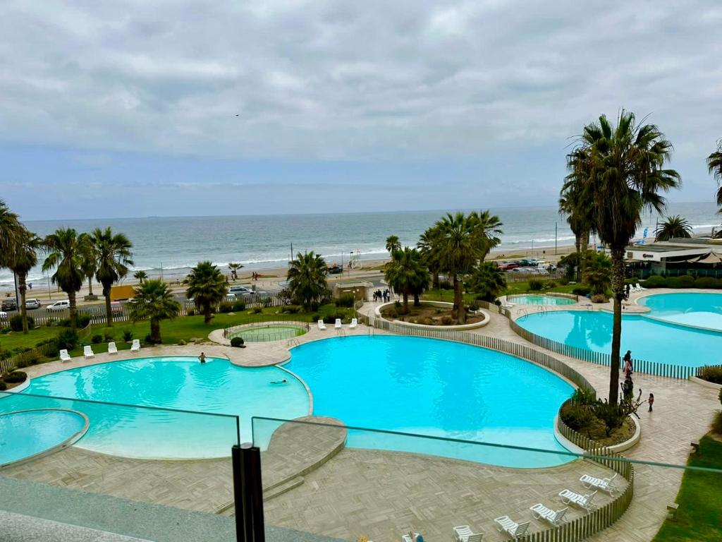 uitzicht op twee zwembaden met palmbomen en het strand bij Departamento Primera Línea Av. Del Mar La Serena in Coquimbo