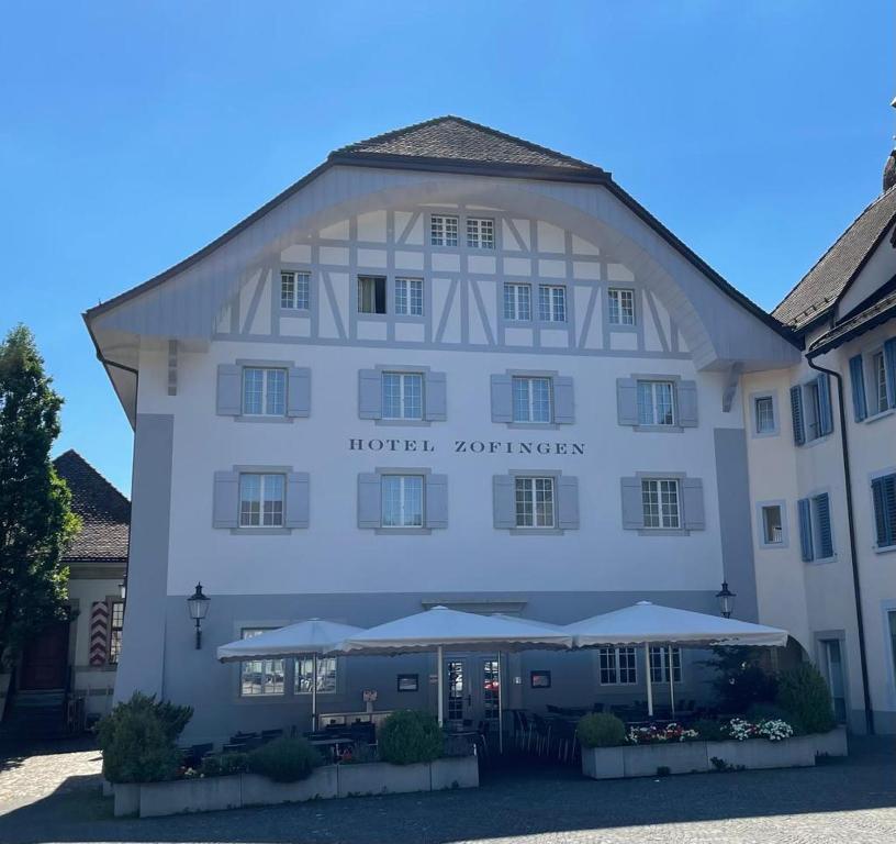 ein großes weißes Gebäude mit Sonnenschirmen davor in der Unterkunft Hotel Zofingen in Zofingen