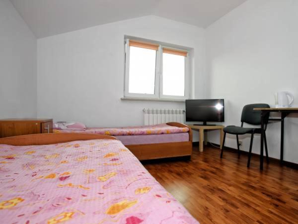 a bedroom with a bed and a desk and a television at Noclegi Pracownicze LAZUR in Ciechanów