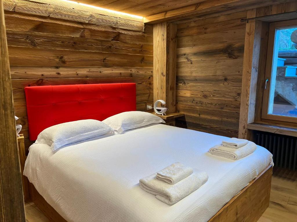 a bedroom with a red headboard and a white bed at CASA VITTORIA in Gignod