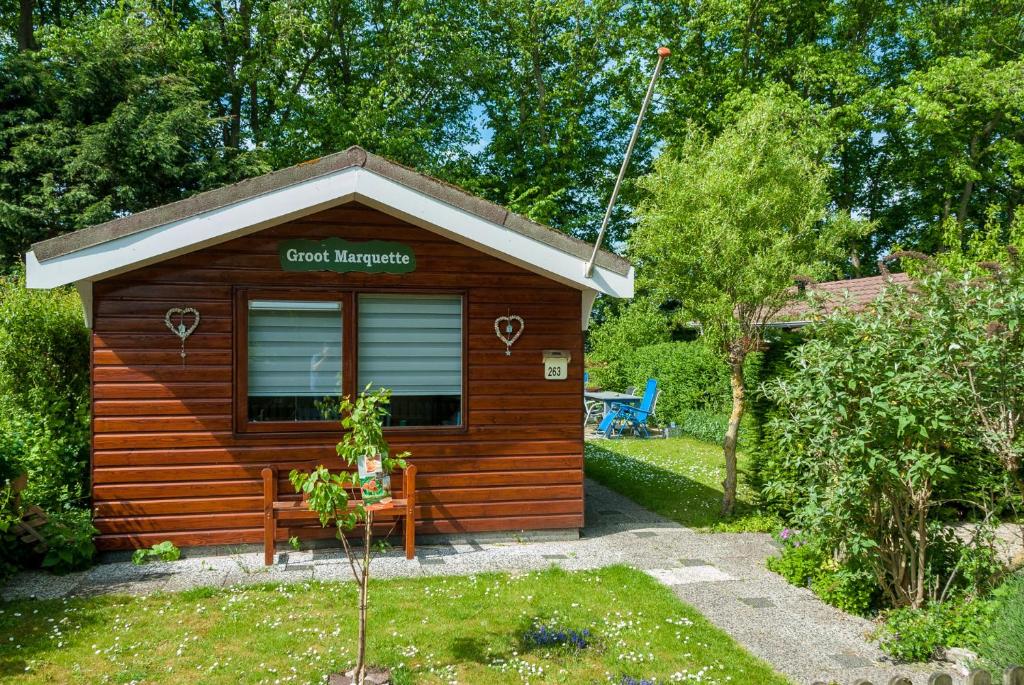 a small wooden shed with a bench in a garden at Groot Marquette - Noord Holland aan uw voeten in Warmenhuizen