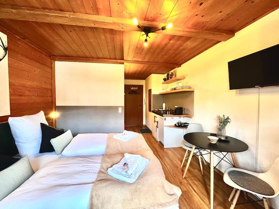 Un dormitorio con una gran cama blanca y una mesa en Ferienwohnung Alpenglühen - mit Sauna & Frühstück, en Schliersee