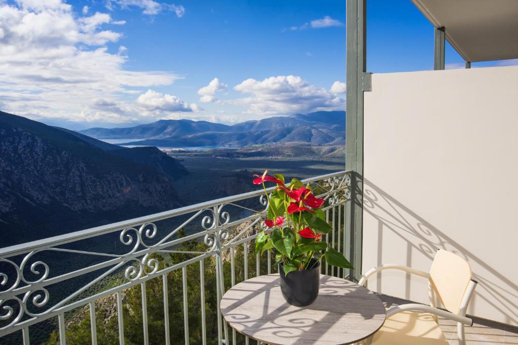 um vaso com flores sentado numa mesa na varanda em V Hotel Delphi em Delfoi