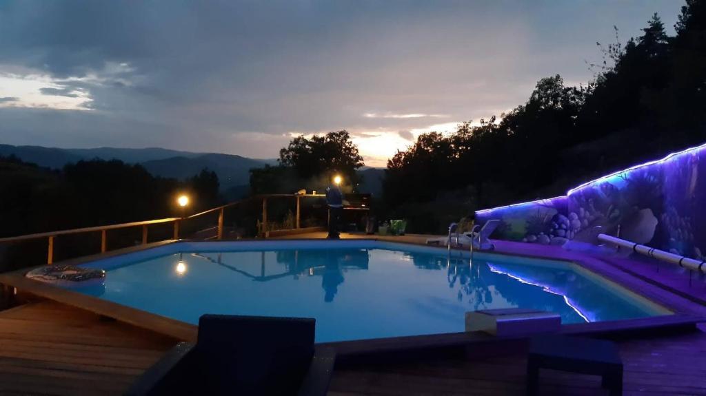 a large swimming pool at night with a view at Le Pas Sage au Trible, Suites Bambou/ La Source/ Tataouine in Gluiras
