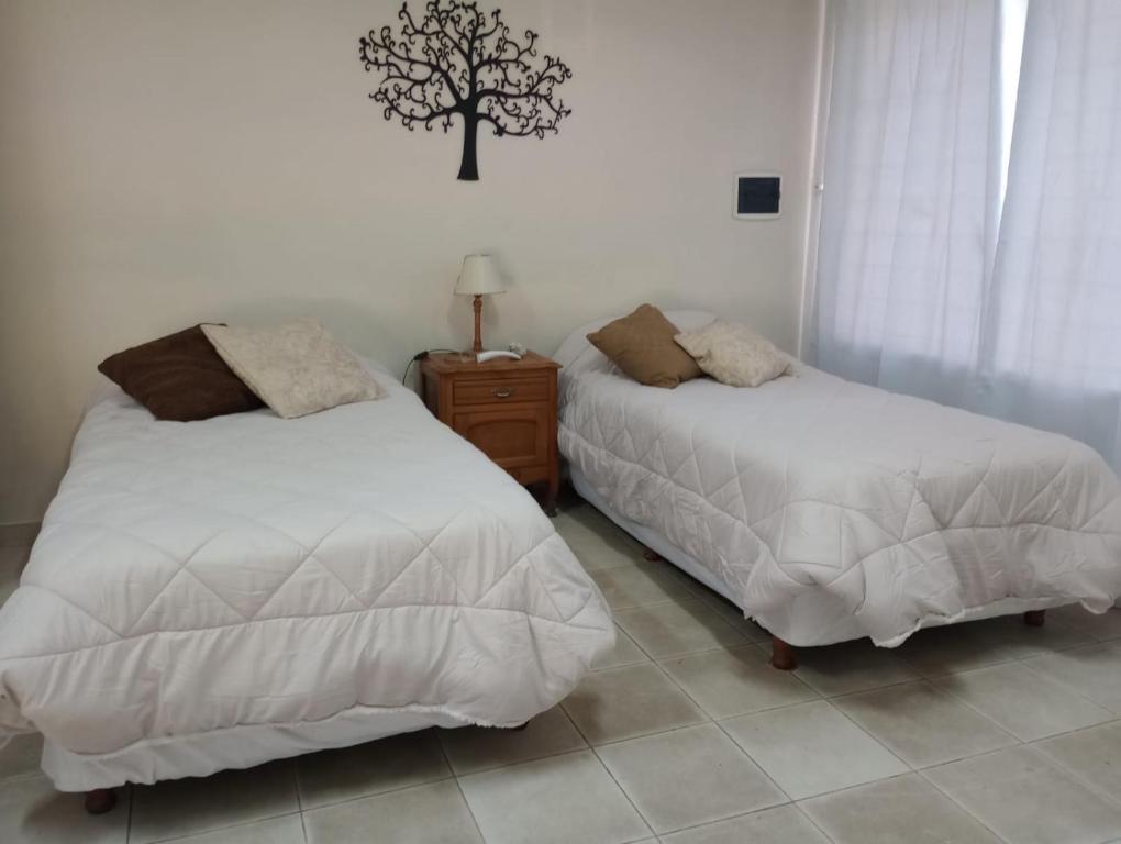 1 dormitorio con 2 camas y un árbol en la pared en MUY LUMINOSO en Lomas de Zamora