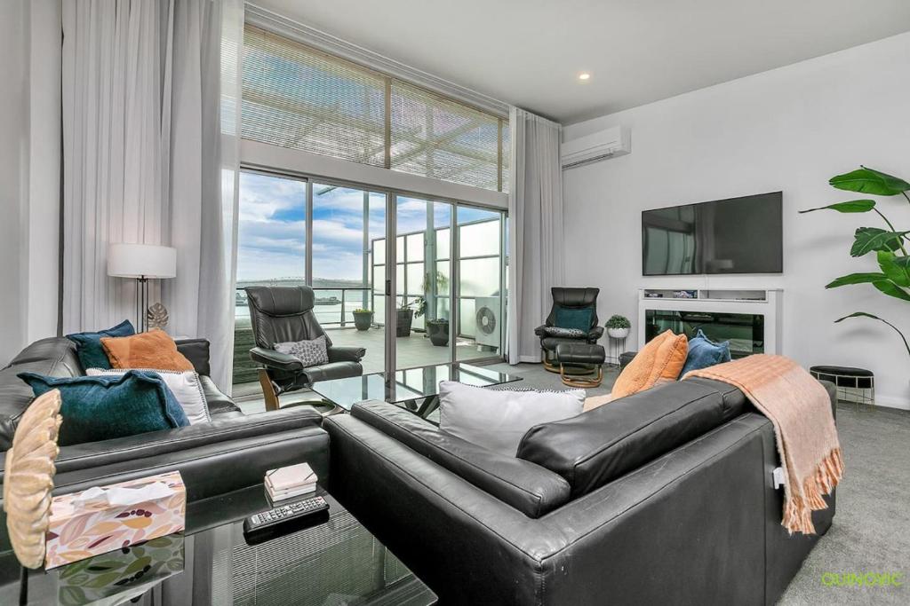 a living room with a leather couch and a tv at AWSA On the Water Luxury (4021) in Auckland