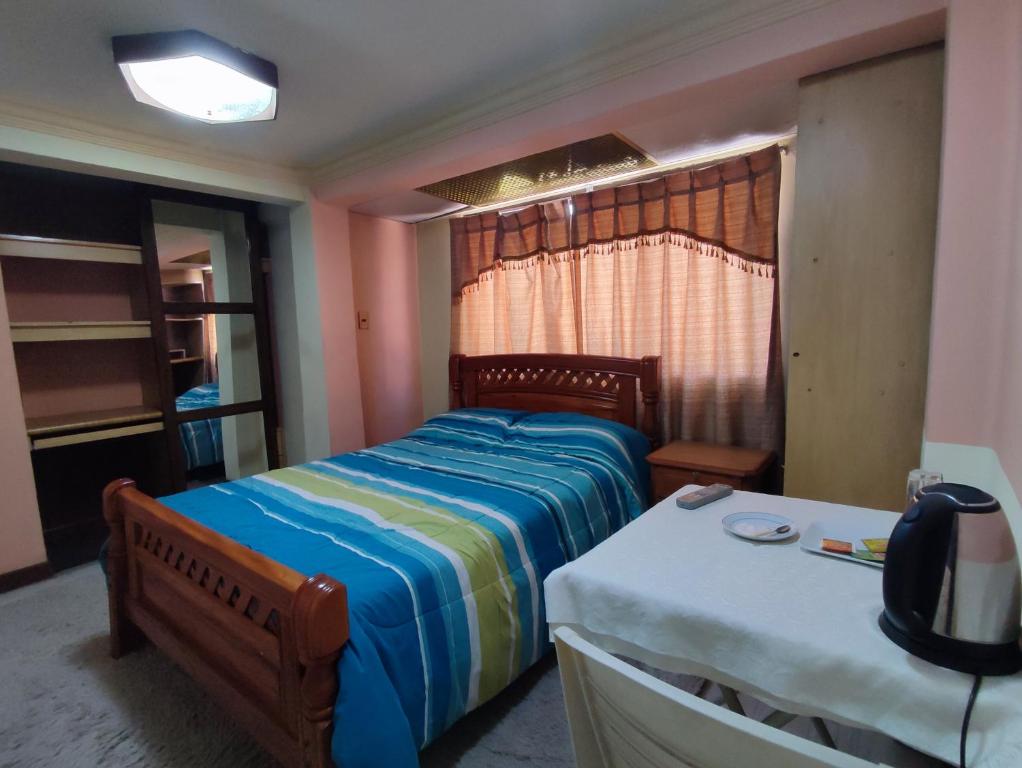 um quarto com uma cama e uma mesa com uma televisão em Villa Real em Oruro