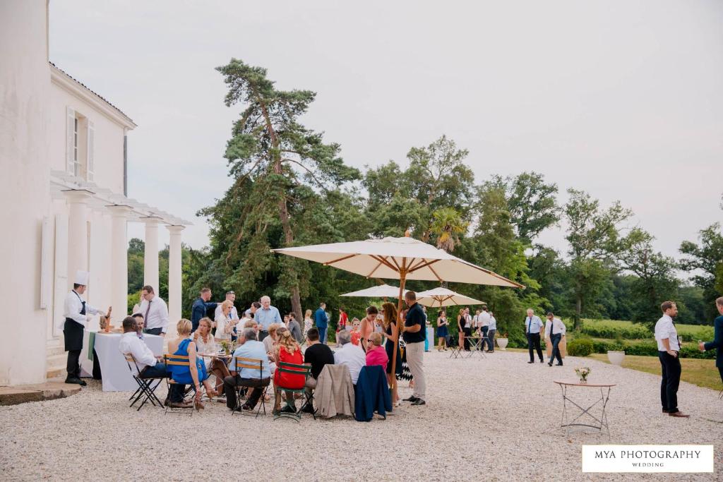 a group of people sitting in chairs under an umbrella at Gîte Château de Seguin in Lignan-de-Bordeaux