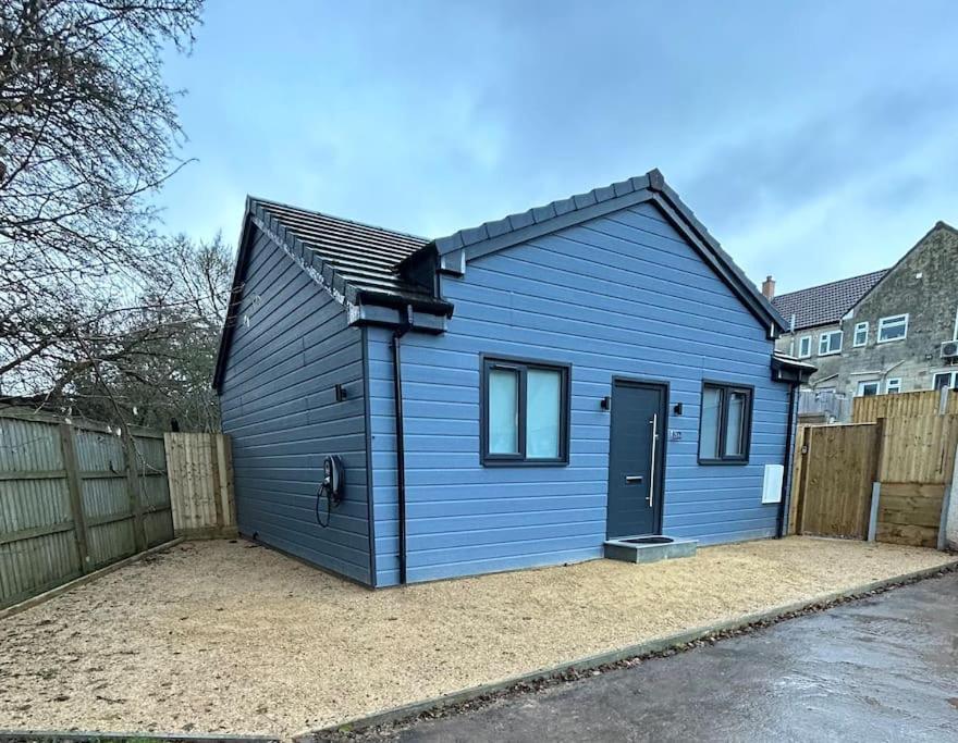 a blue house with a door in a yard at New Build Cosy Bungalow near Bath and Bristol in Wick