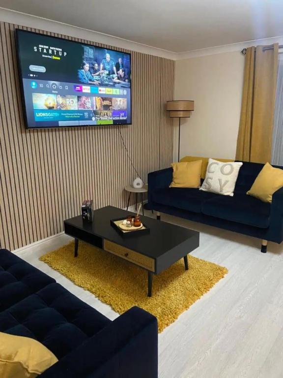 a living room with a couch and a tv at Cozy House, Garden, Free Parking, Opposite Train station with Disneyplus & Netflix included in West Thurrock