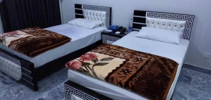 Hotel Sky Inn Clifton في كراتشي: سريرين في غرفة مع سريرين sidx sidx