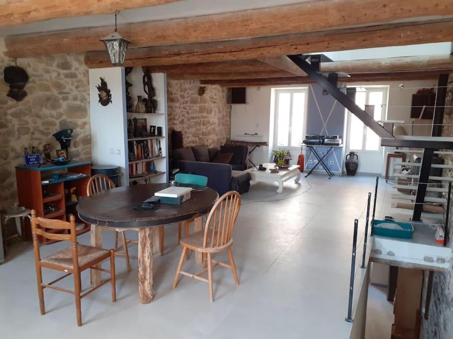 een woonkamer met een houten tafel en stoelen bij Maison restaurée à l'ancienne avec terrasse in Jouques