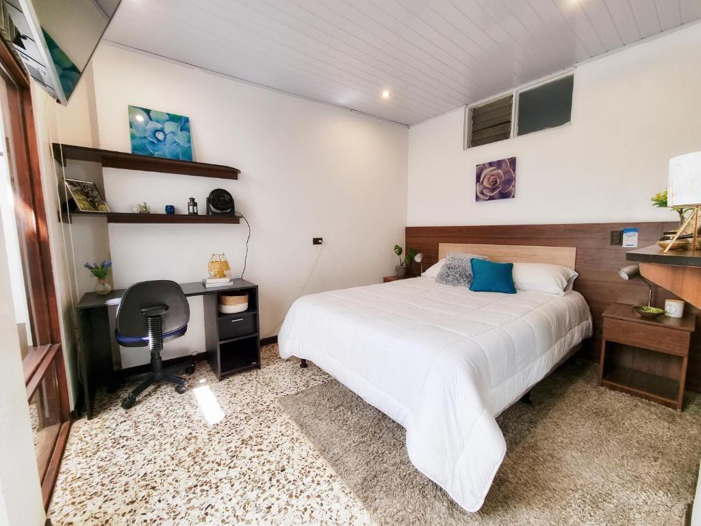 a bedroom with a bed and a desk and a computer at 714 Studios in San José