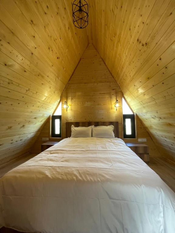 uma grande cama branca num quarto de madeira em A Frame Denver em Ashtarak