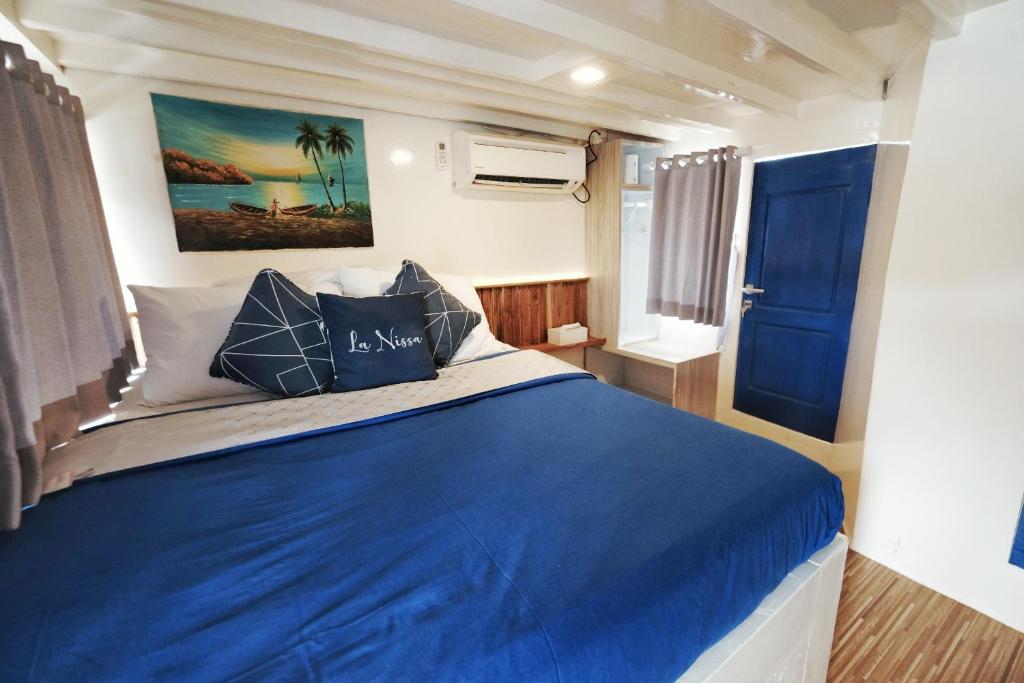 um quarto com uma cama com lençóis azuis e uma porta azul em Phinisi sailing Komodo 3 days 2 night em Labuan Bajo