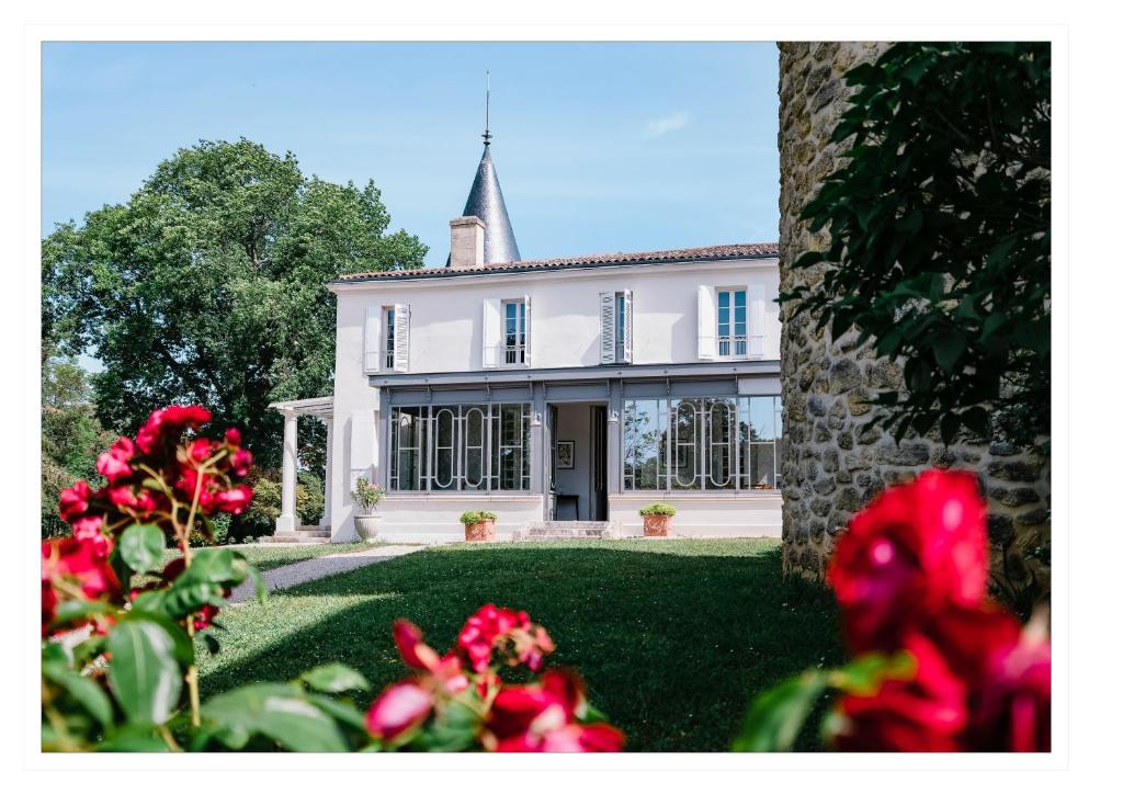 a large white house with a tower on top of it at Gîte Château de Seguin in Lignan-de-Bordeaux