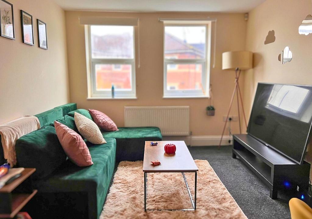a living room with a green couch and a table at Charming Flat in Central Bristol in Bristol