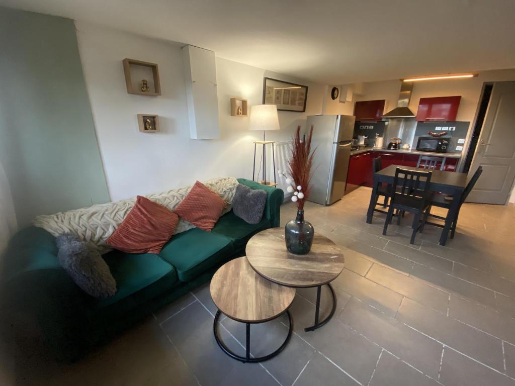 a living room with a green couch and a table at Le Jardin de Sasha in Équemauville